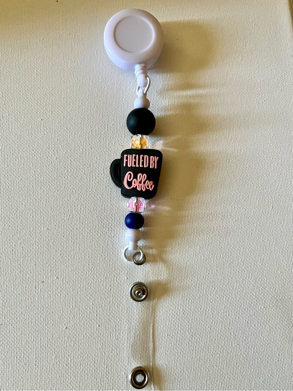 White Retractable Badge Reel with 'Fueled by Coffee' Black Charm